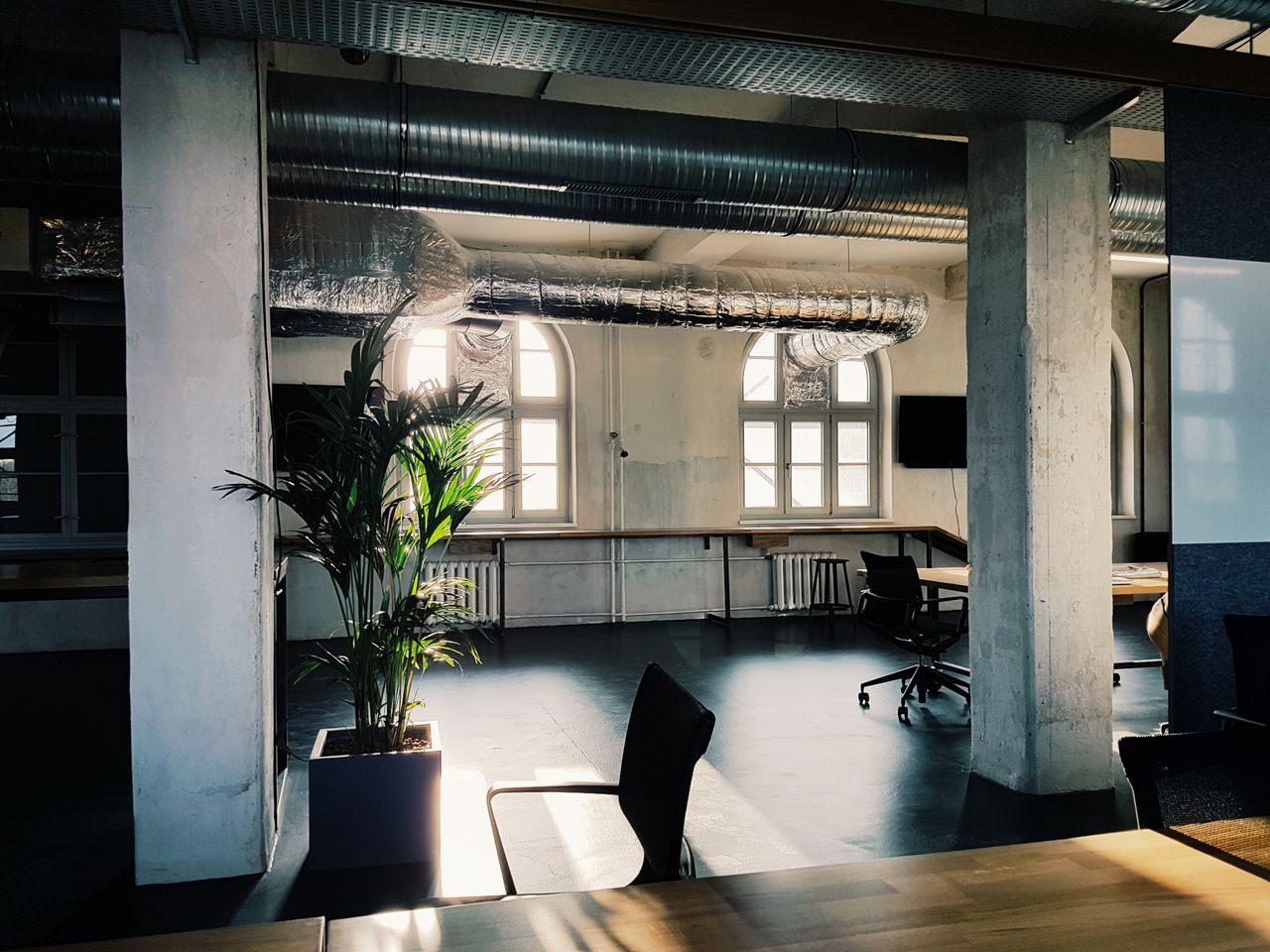 contact Bright modern office interior with industrial design elements and natural light through large windows.
